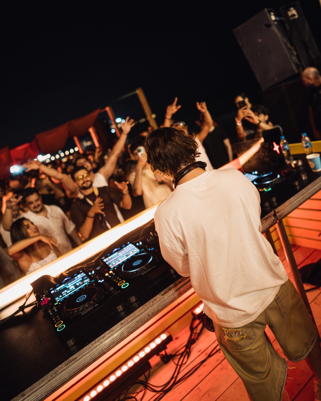 Crowd with hands up behind the booth at a beach party