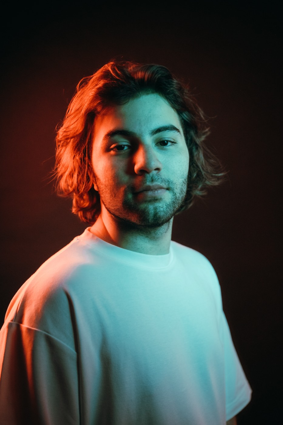 A DEEN portrait in red and teal light, white t-shirt